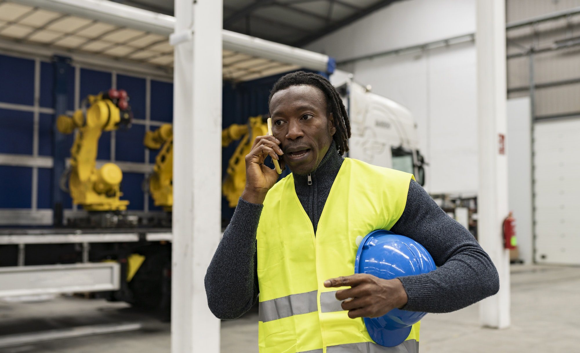 african man freight worker talking on the phone next to the truck - goods delivery concept -